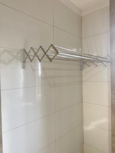 a shower with a white tiled wall with a metal rack at AP+preço popular+ar condicionado+internet 300mb in Goiânia
