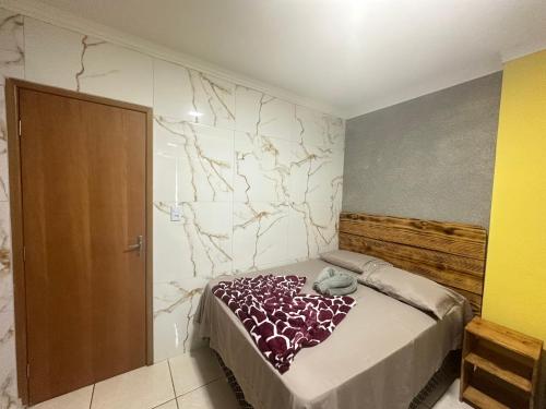 1 dormitorio con cama y pared de mármol en AP+preço popular+ar condicionado+internet 300mb en Goiânia