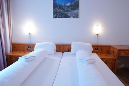 a bedroom with two beds with white sheets and two lights at Hotel Schiffahrt in Mols