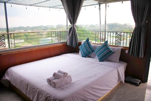 łóżko z ręcznikami w pokoju z oknem w obiekcie Homestay Măng Đen - ALamer w mieście Kon Von Kla