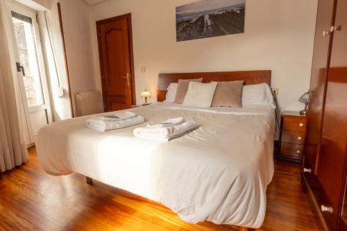 1 dormitorio con 1 cama blanca grande y toallas. en Arritokieta - ONGI ETORRI, en Zumaia