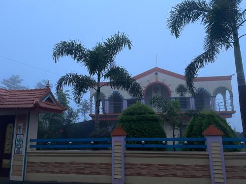 a house with palm trees in front of a fence at Best Mist in Idukki