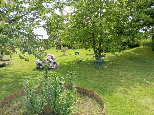 a garden with chairs and a table and flowers at La Gerbaudiere Chambres&Table d hotes proche Mont Saint Michel CUISINE MAISON in Notre-Dame-du-Touchet