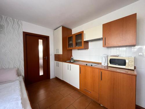 a small kitchen with wooden cabinets and a microwave at Penzion Relax Martina in České Budějovice