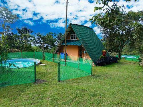 a house with a green fence and a swimming pool at Glamping eco descanso la vega Nocaima in Nocaima