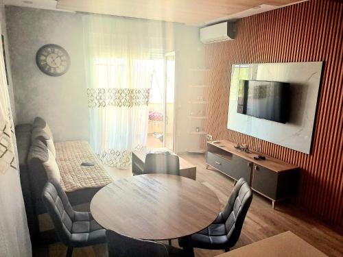 Una sala de estar con una mesa y sillas y un televisor. en Apartment AS, en Ulcinj