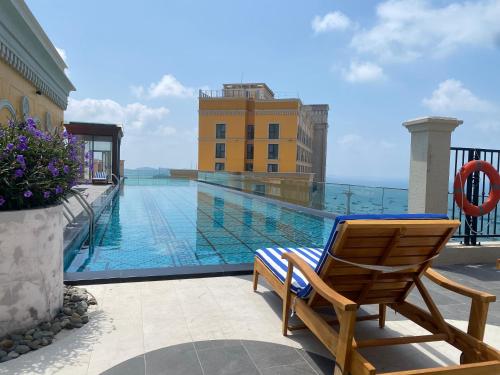 une chaise sur un balcon avec une piscine dans l'établissement Le Ciel Phu Quoc - Hillside Apartment, à Duong Dong