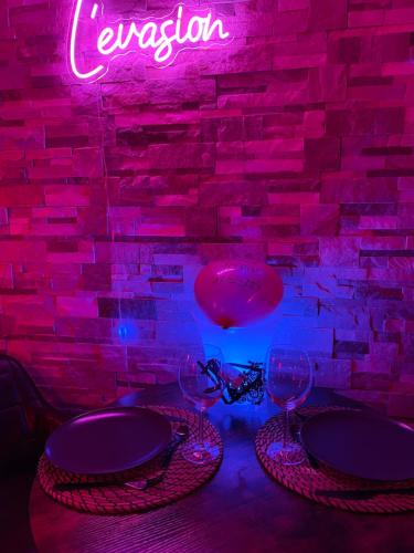 a table with two wine glasses and a neon sign at L’Evasion la Love Room de Fayence in Fayence