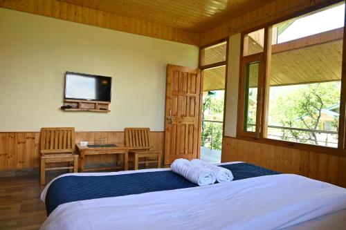 a bedroom with two beds and a tv on the wall at Cascade Mountain Retreat Manali in Manāli
