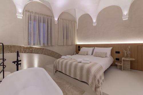 a white bedroom with a bed and a bath tub at Pànto - Rooftop boutique rooms in Palermo