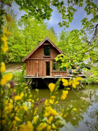 a small wooden house on a dock in the water at Leśna Chatka z prywatnym stawem, jezioro, sauna in Drzewiany
