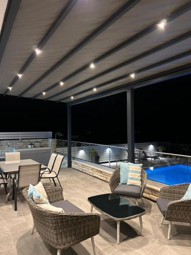 a patio with chairs and tables and a swimming pool at Alkiviades Villa in Theletra