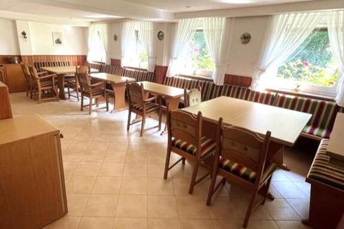 a dining room with tables and chairs and windows at Haus PANORAMA - Appartement Auszeit 5 in Braunlage