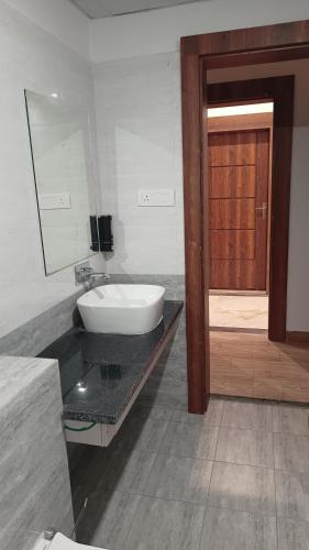 a bathroom with a sink and a mirror and a door at Hotel Swastik Bhumi in Gaya