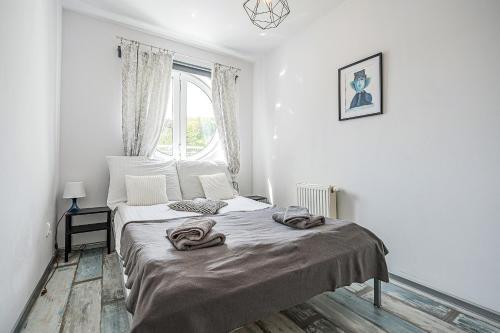 a white bedroom with a bed with towels on it at Pomorskie Apartamenty Bernadowska B&W in Gdynia