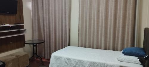 a room with a bed and a table and a window at Pousada da Paz in Curitiba