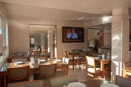 un restaurante con mesas y sillas y TV en la pared en Marechal Plaza Hotel en São Gabriel