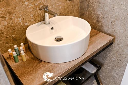 a white sink sitting on a wooden counter with two cosmetics at Domus Marina - Ionio room in Mondragone