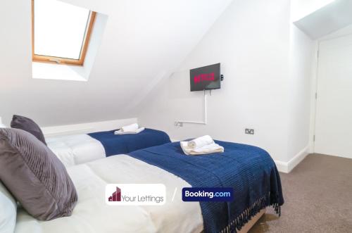 1 dormitorio con 2 camas y TV en la pared en Stylish 2 Bedroom Apartment By Your Lettings Short Lets & Serviced Accommodation Peterborough With Free WiFi,Parking And More en Huntingdon