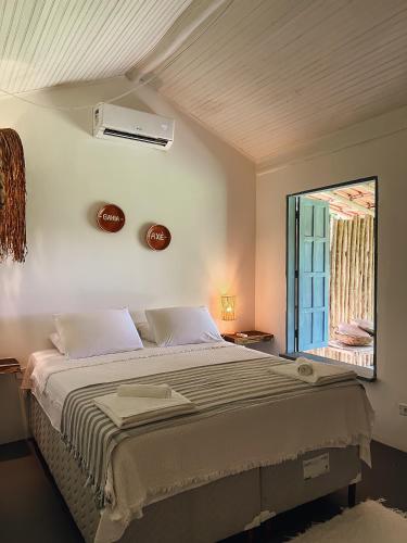 a bedroom with a large bed and a window at Pousada Quintal Caraíva in Caraíva