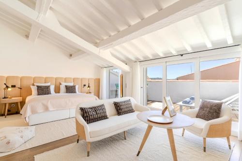 サントロペにあるVillas by Le Yaca Saint-Tropezのベッドルーム1室(ベッド1台、ソファ、テーブル付)