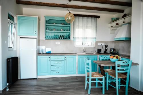 una cocina con armarios azules y una mesa con sillas en Filokalia 5 Veins - Vacation House With Sea View, en Caristo