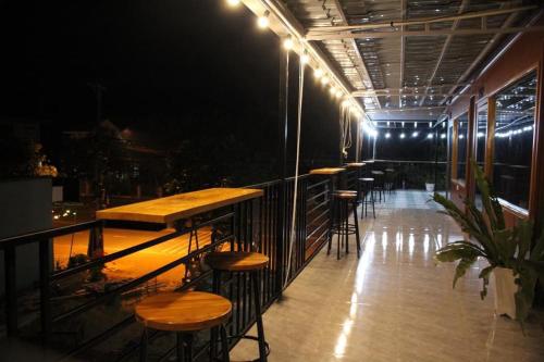 una fila de mesas y taburetes en un balcón por la noche en Homestay Măng Đen - ALamer, en Kon Von Kla