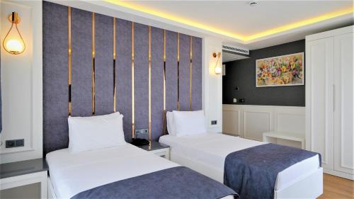 a hotel room with two beds and a wall at Mai İnci Otel in Antalya