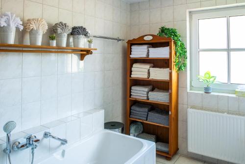 uma casa de banho com uma banheira branca e uma prateleira com toalhas em Ferienhaus Eisenach em Eisenach