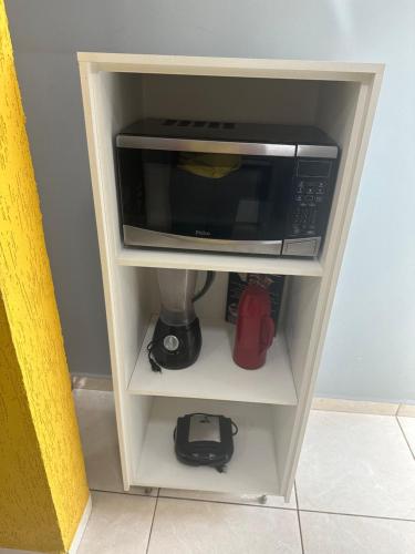 a microwave on a shelf in a kitchen at AP inteiro com ar condicionado in Goiânia