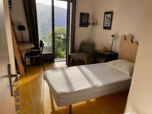 une chambre avec un lit, une chaise et une fenêtre dans l'établissement Maison indépendante à Sainte-Lucie de Tallano, à Santa-Lucia-di-Tallano