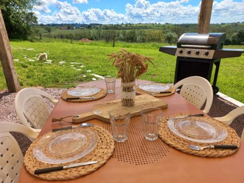 une table avec des assiettes, des verres et un grill dans l'établissement Tipi du petit villers, à Le Brethon