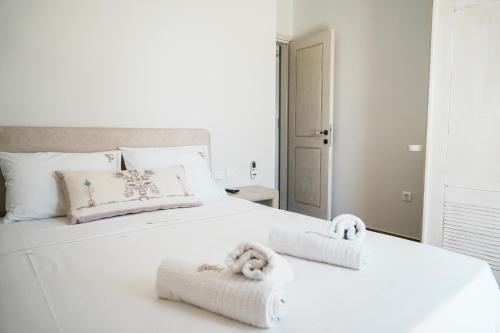 Un dormitorio con una cama blanca con toallas. en Filokalia 4 Veins - Vacation House with Sea View, en Caristo