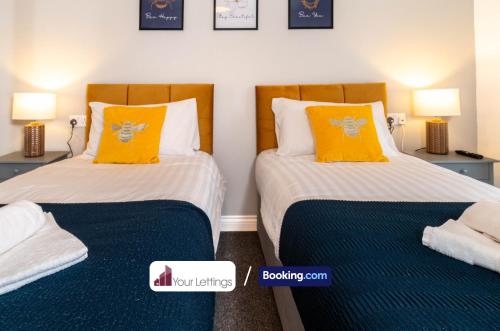 2 camas con almohadas de color naranja en una habitación en Luxury 6 Bedroom Contractor House By Your Lettings Short Lets & Serviced Accommodation Peterborough With Free WiFi, en Peterborough