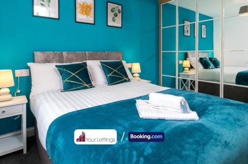Un dormitorio azul con una cama con toallas. en Luxury 6 Bedroom Contractor House By Your Lettings Short Lets & Serviced Accommodation Peterborough With Free WiFi, en Peterborough