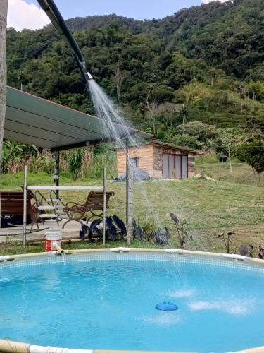 a pool with a sprinkler spraying water over it at Glamping eco descanso la vega Nocaima in Nocaima
