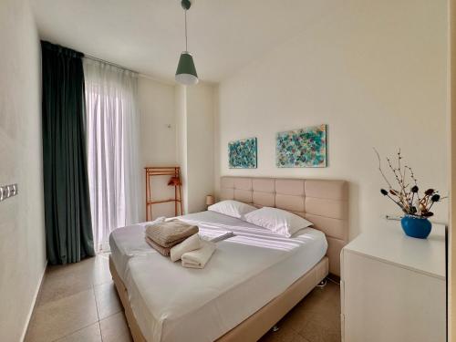 a bedroom with a large white bed and a window at Green Coast, Palase 148 in Palasë