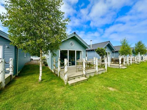 a blue house with a porch and a yard at Azure Beach House - Part of the The Bay Filey Holiday Village with pool, gym and direct beach access, pub, restaurant, tennis and meadows walks in Filey
