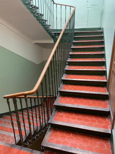 a staircase with red and black steps and a green rail at L'Adrion in Draguignan