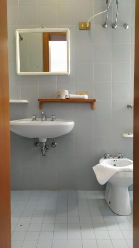 a bathroom with a sink and a mirror and a toilet at Villa Serena in Lignano Sabbiadoro