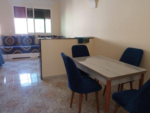 a dining room with a table and blue chairs at Bilal appartement in Larache