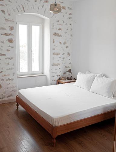 a bedroom with a white bed with a window at Militiko in Himare