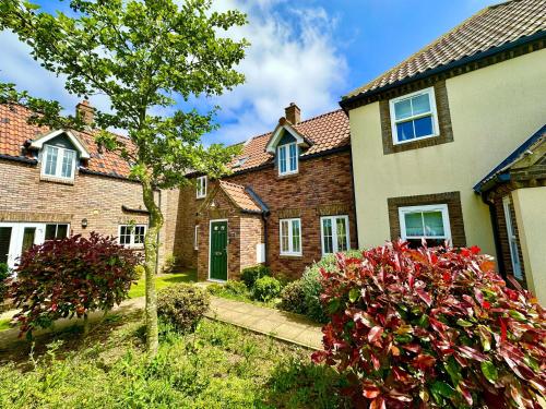 a large brick house with a tree in the yard at Puddleduck Cottage - Part of the The Bay Filey Holiday Village with pool, gym and direct beach access, pub, restaurant, tennis and meadows walks in Filey