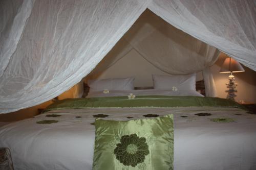 a bedroom with a canopy bed with a green pillow at Joglo On The Beach in Lovina