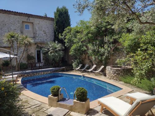 - une piscine dans une cour avec des chaises et une maison dans l'établissement La Maison Des Autres, piscine chauffée, chambres d'hôtes proches Uzès, Nîmes, Pont du Gard, à Saint-Géniès-de-Malgoirès