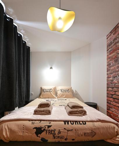 une chambre avec un grand lit avec un mur de briques dans l'établissement L'urbain, à Arras