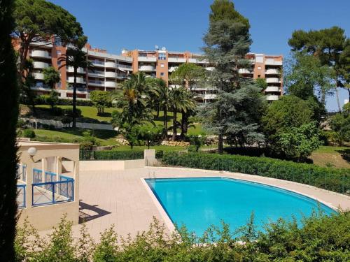 une piscine en face d'un grand bâtiment dans l'établissement Confortable 2P 50m2 dans Beau Parc,Piscine,Tennis, à Cannes