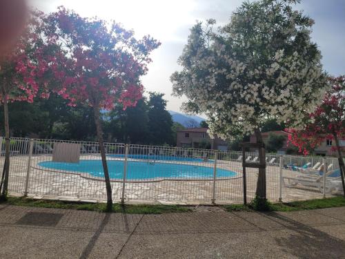 une piscine derrière une clôture avec deux arbres dans l'établissement Les villas de melody, à Moriani-Plage