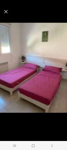 - 2 lits dans une chambre avec des draps violets dans l'établissement Les villas de melody, à Moriani-Plage