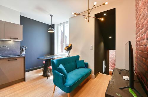 un salon avec une chaise bleue et une cuisine dans l'établissement L'urbain, à Arras